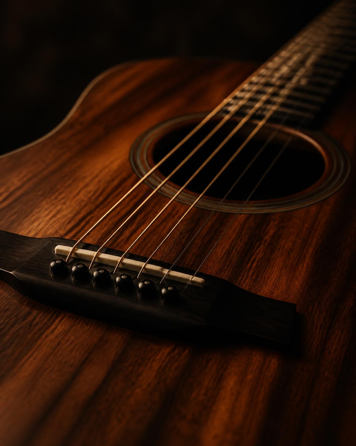 Close-up of a warm wooden acoustic guitar under low amber light
